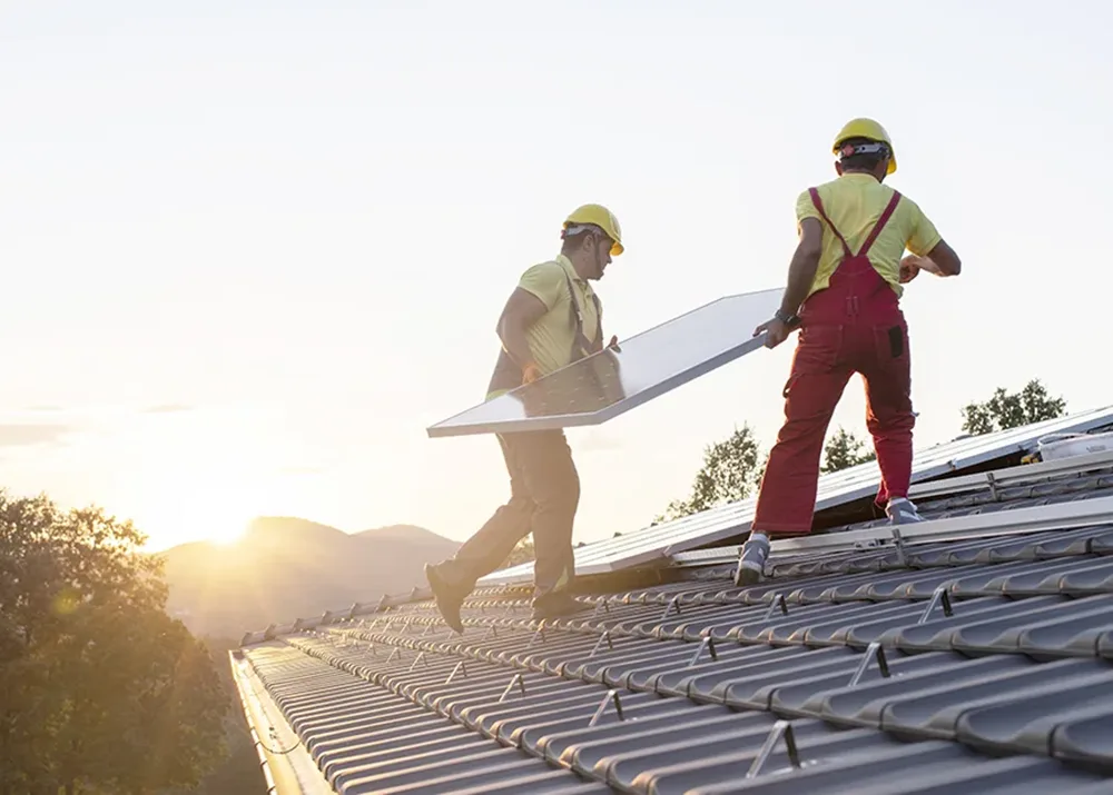 Two workers installing solar panels on a roof.