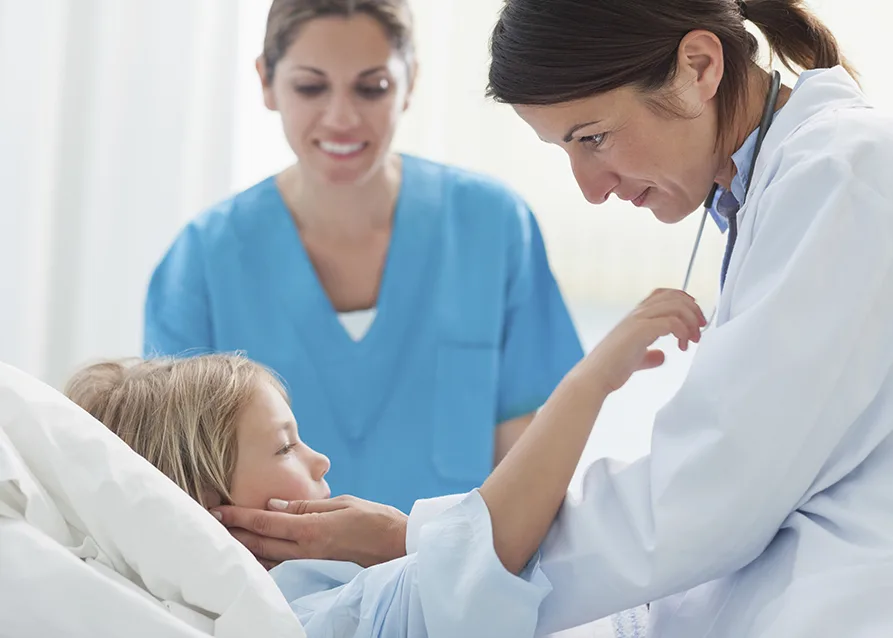 A doctor and a nurse are checking on a little kid in a hospital.