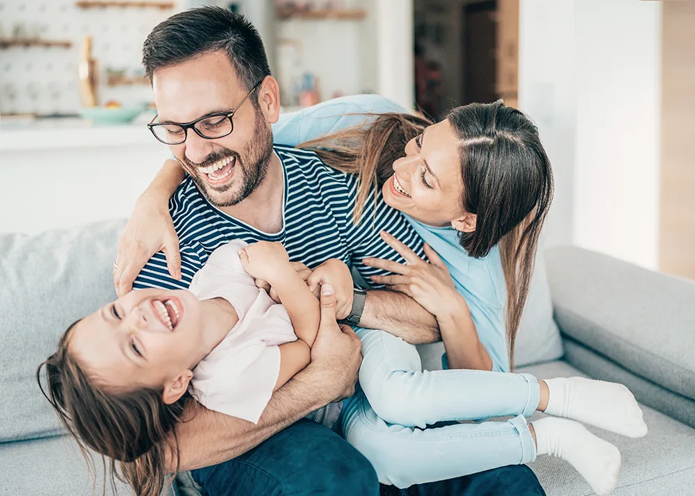 Happy mother and father play with their daughter