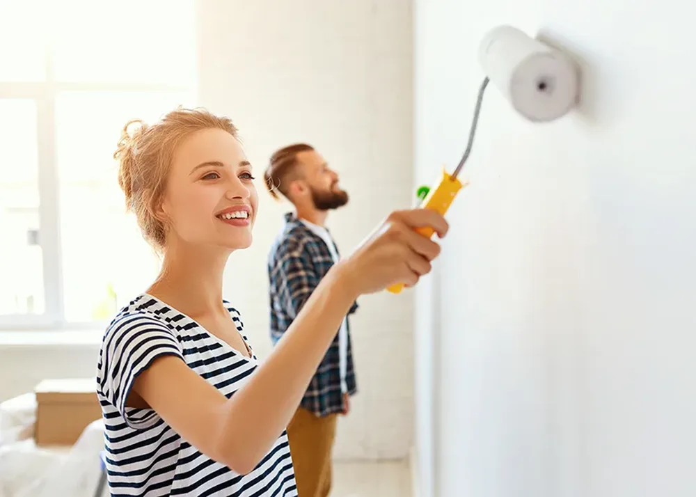 A woman and a man are painting a wall.