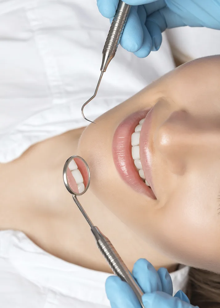 Dentist holding tools near the face of a patient.