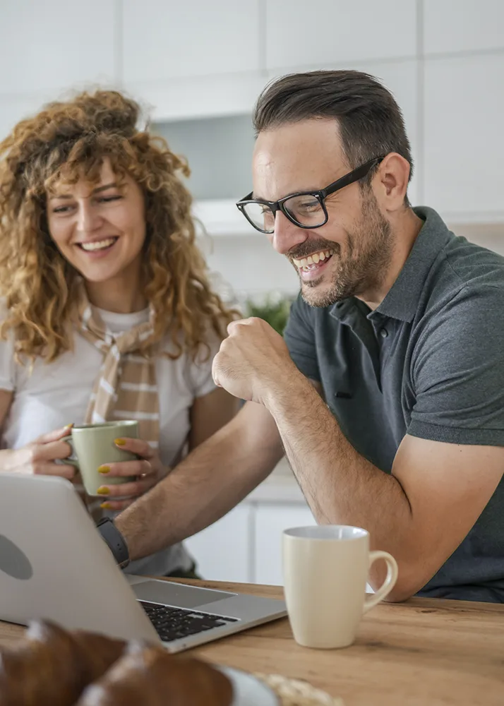 Smiling man and woman using a laptop to search for insurance on the ACA marketplace.