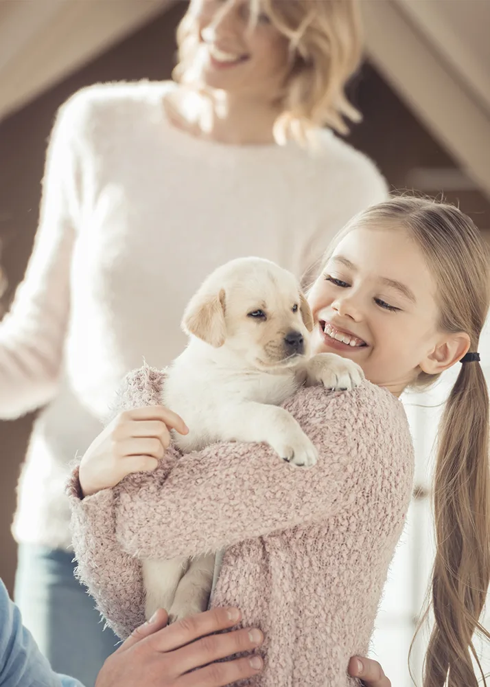 A young girl hugging a puppy.