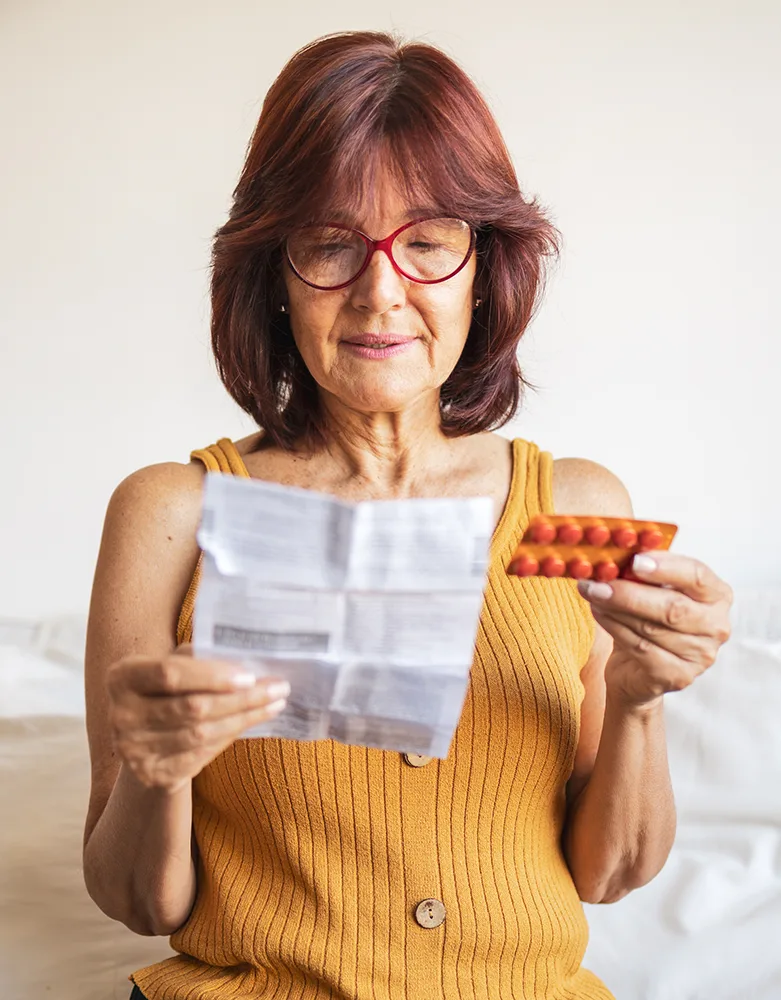 An older woman reading an instruction for the medicine she bought with prescription insurance.
