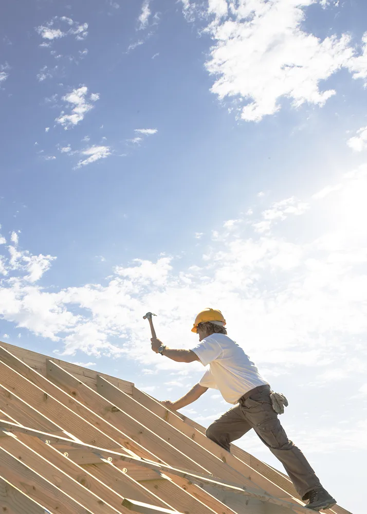 Roofer in a hard hat working on a roof.