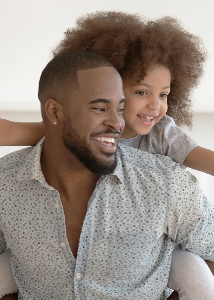 A happy father carrying his daughter on his back.