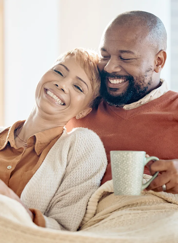 A happy husband holding a cup and hugging his wife.